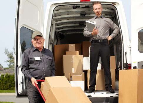 Moving van and helper loading household items for a removal service